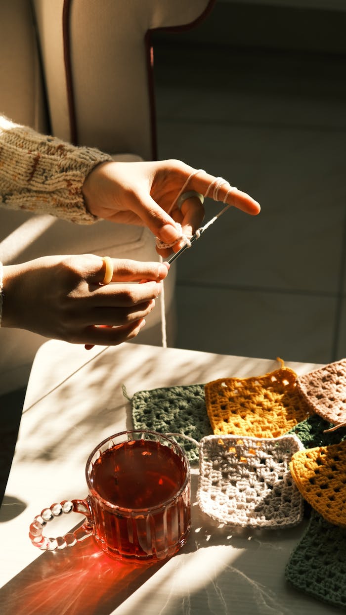 Warm sunlight illuminates knitting and tea, creating a cozy atmosphere.