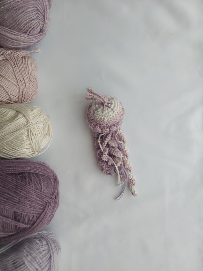 Colorful crochet jellyfish surrounded by skeins of yarn on a flatlay.